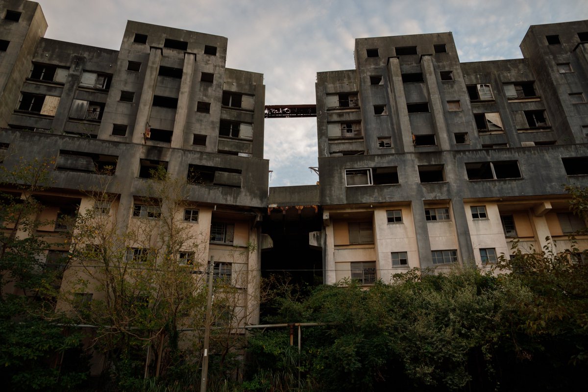 battenkusa's tweet photo. そして池島廃墟群のボス、8階建てアパート群。
夕方に訪れたので威圧感がすごい。
エレベーターが無いために独特のギミックを備えていて、裏側の高台から5階にアクセスできるようになっているそうで、5～8階の住人はそこから入れば簡単アクセスできるようになっているらしい。最上階渡り廊下も見えるね、スリル満点そうだけど。