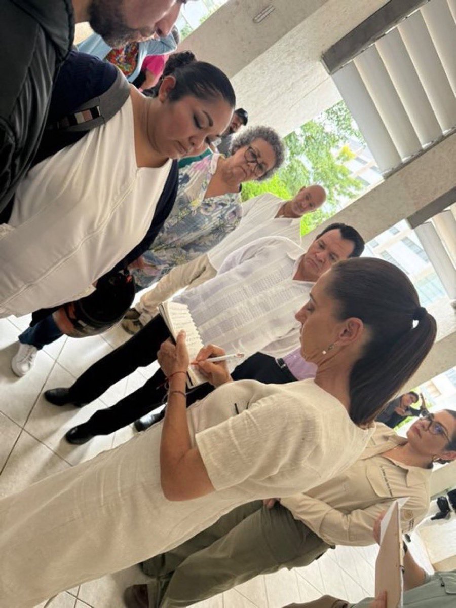 DeniseDresserG's tweet photo. La ironía en una foto: Claudia Sheinbaum, quien ha minimizado el desabasto de medicamentos y la crisis del sistema de salud, ahora recorre clínicas del IMSS tomando apuntes en una libretita para averiguar qué falta. Después de ocho años de gobiernos de Morena, ¿apenas están haciendo el diagnóstico? ¿Cuántos años más necesitarán para encontrar las soluciones?