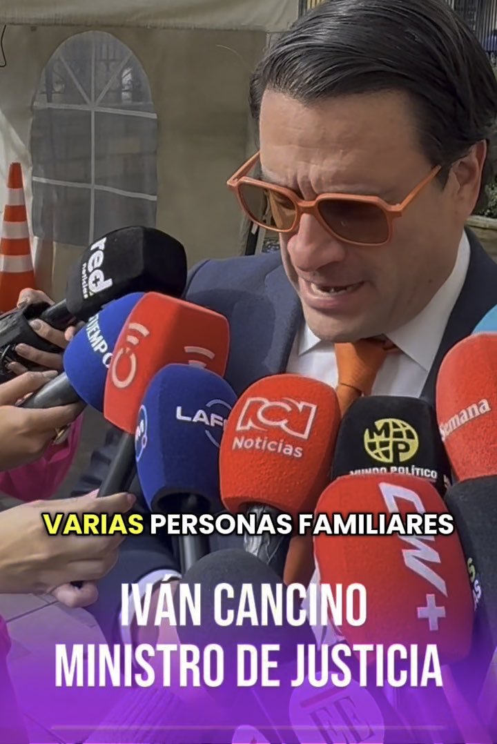A man in a suit and orange-tinted sunglasses speaks into multiple press microphones; on-screen text identifies him as 'IVÁN CANCINO MINISTRO DE JUSTICIA' with the caption 'VARIAS PERSONAS FAMILIARES'.