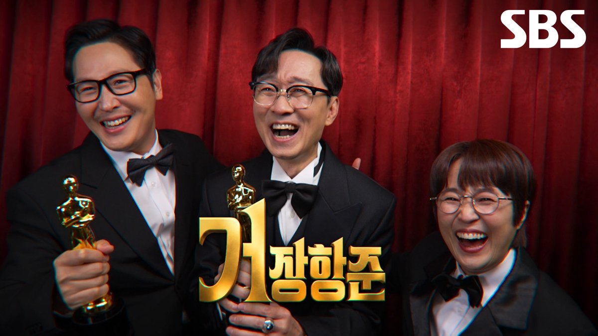 Three joyful hosts dressed in formal tuxedos pose together against a red velvet curtain backdrop, holding golden Oscar-style trophies as they laugh enthusiastically. The image features the SBS logo in the top right corner and the golden Korean title "거장항준" (The Great Hang-jun) prominently displayed in the center, promoting the upcoming SBS Thursday variety talk show hosted by Jang Hang-jun, Song Eun-i, and Kim Poong.