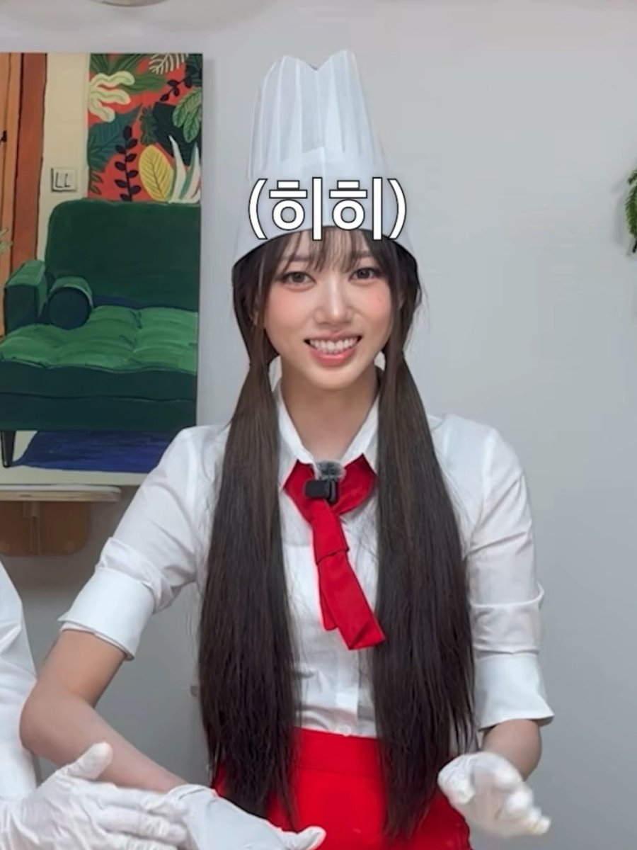 A young woman wearing a chef's hat, white shirt, red tie, and white gloves smiles at the camera, with Korean text '(히히)' overlaid, likely a screenshot from a livestream.