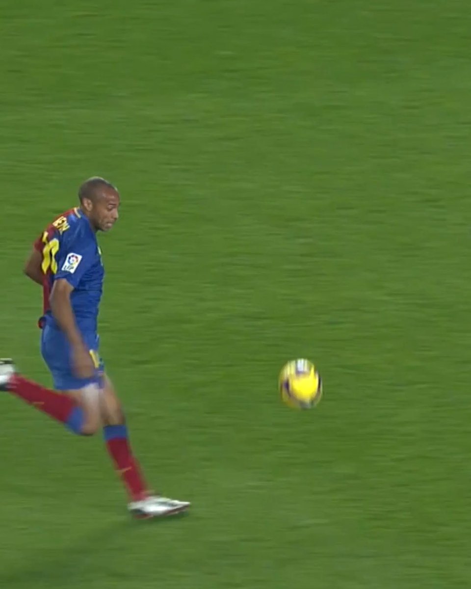 A soccer player in a blue and red jersey (appears to be #28, possibly Henry) runs toward a ball on a green field during a match.