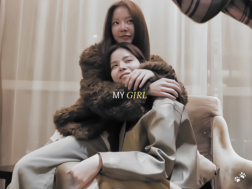 A photograph of two women hugging, one standing behind the other on a white chair, overlaid with the text 'MY GIRL' in white and yellow.