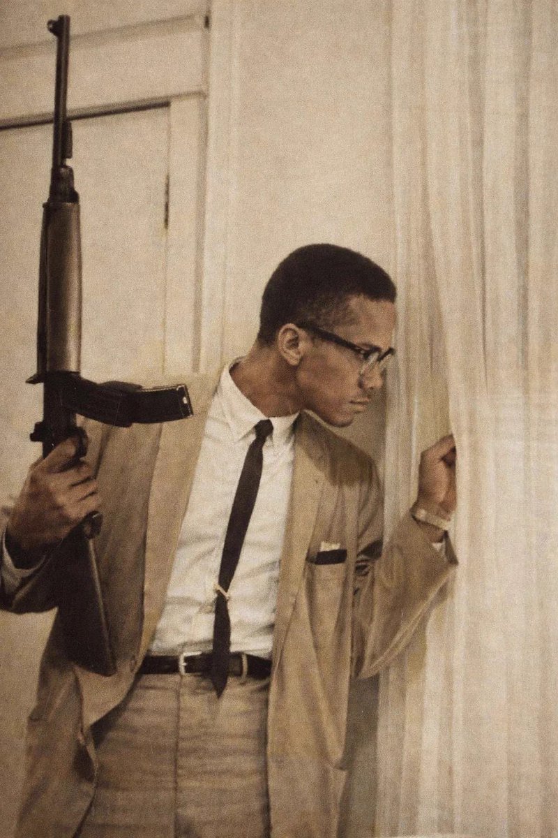 BmediaHQ's tweet photo. Malcolm X holding a Rifle while guarding his family, 1964.

By this point, Malcolm had broken publicly with the Nation of Islam, a split that left him politically isolated and personally vulnerable. After denouncing its leadership and founding the Organization of Afro American Unity, he began receiving repeated death threats. His home in Queens had already been firebombed while his wife and children were inside.
Contrary to popular portrayals, Malcolm X was not advocating violence for its own sake. He argued that nonviolence was a strategy, not a moral absolute, and that it should not be demanded of people who were already under attack.
Added fact:
Less than a year after this photo was taken, Malcolm X was assassinated on February 21, 1965, while preparing to speak at the Audubon Ballroom in Harlem.
