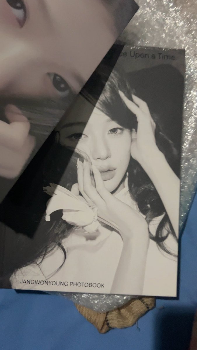 A close-up photo of a photobook titled 'JANGWONYOUNG PHOTOBOOK' with 'Once Upon a Time' visible at the top, showing a black and white portrait of a woman with long dark hair posing with her hands near her face.
