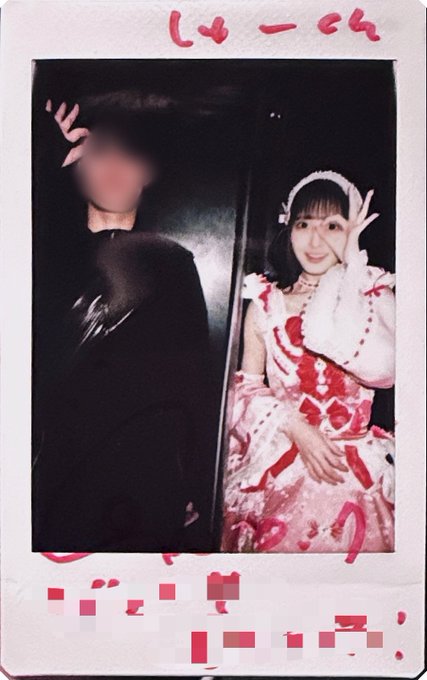 A polaroid-style photo showing two people, with one person on the left blurred out and a smiling young woman on the right wearing a frilly red and white outfit, posing with a peace sign. Red handwritten text is partially obscured at the top and bottom.