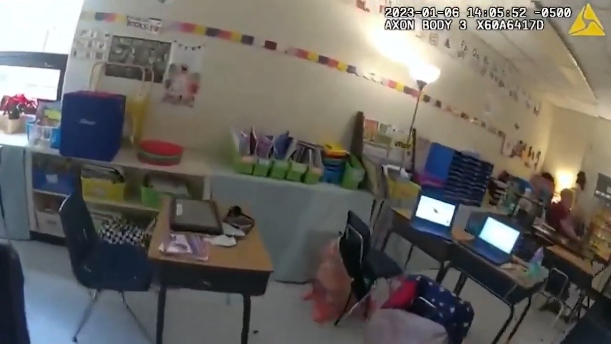 A timestamp of "2023-01-06 14:05:52 -0500" and "AXON BODY 3 X60A6417D" are seen in the top right corner of a body camera image showing a classroom with desks and chairs. The image likely depicts the classroom scene following the reported shooting incident.