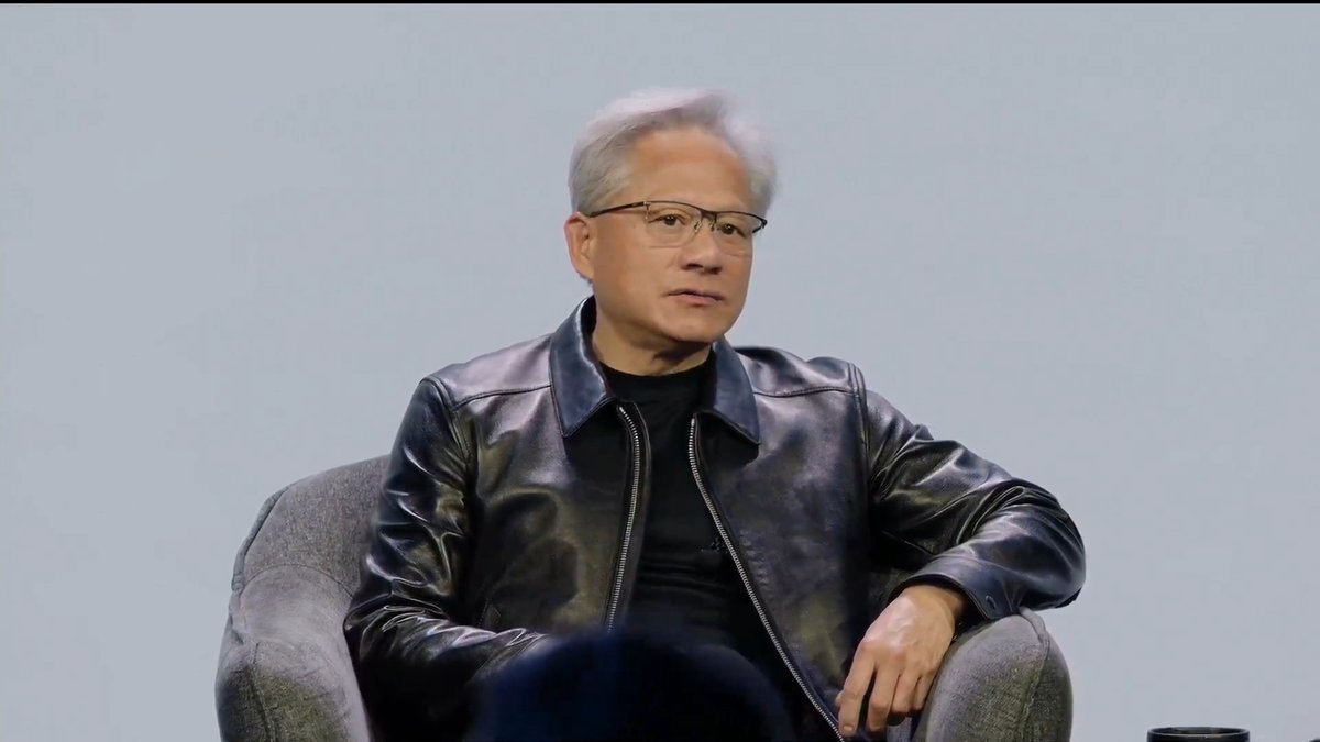 Jensen Huang, the founder and CEO of Nvidia, sits on a stage in a black leather jacket, appearing thoughtful during what looks like an interview or fireside chat. His presence directly ties to the accompanying statement about Nvidia's early reliance on the Windows operating system, which he credits as foundational to the company's existence.