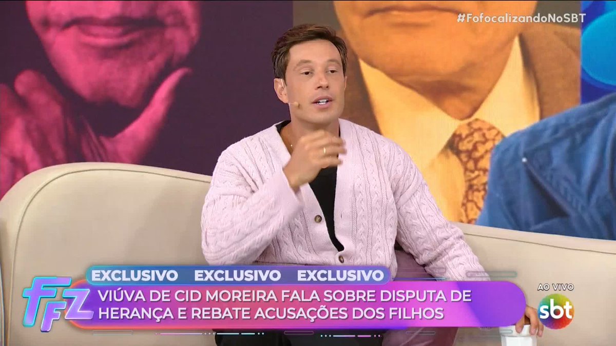 A TV host on SBT's "Fofocalizando" (#FofocalizandoNoSBT) sits on a cream couch wearing a pink cardigan, speaking into a lapel mic while gesturing, with a chyron reading "EXCLUSIVO: VIÚVA DE CID MOREIRA FALA SOBRE DISPUTA DE HERANÇA E REBATE ACUSAÇÕES DOS FILHOS," previewing the program's upcoming coverage of the inheritance dispute and accusations between Cid Moreira's widow and his children.