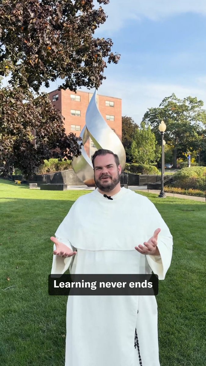 A man in a white religious habit stands on a grassy lawn with his arms open, captioned 'Learning never ends', with a large metallic teardrop sculpture and a brick building behind him.