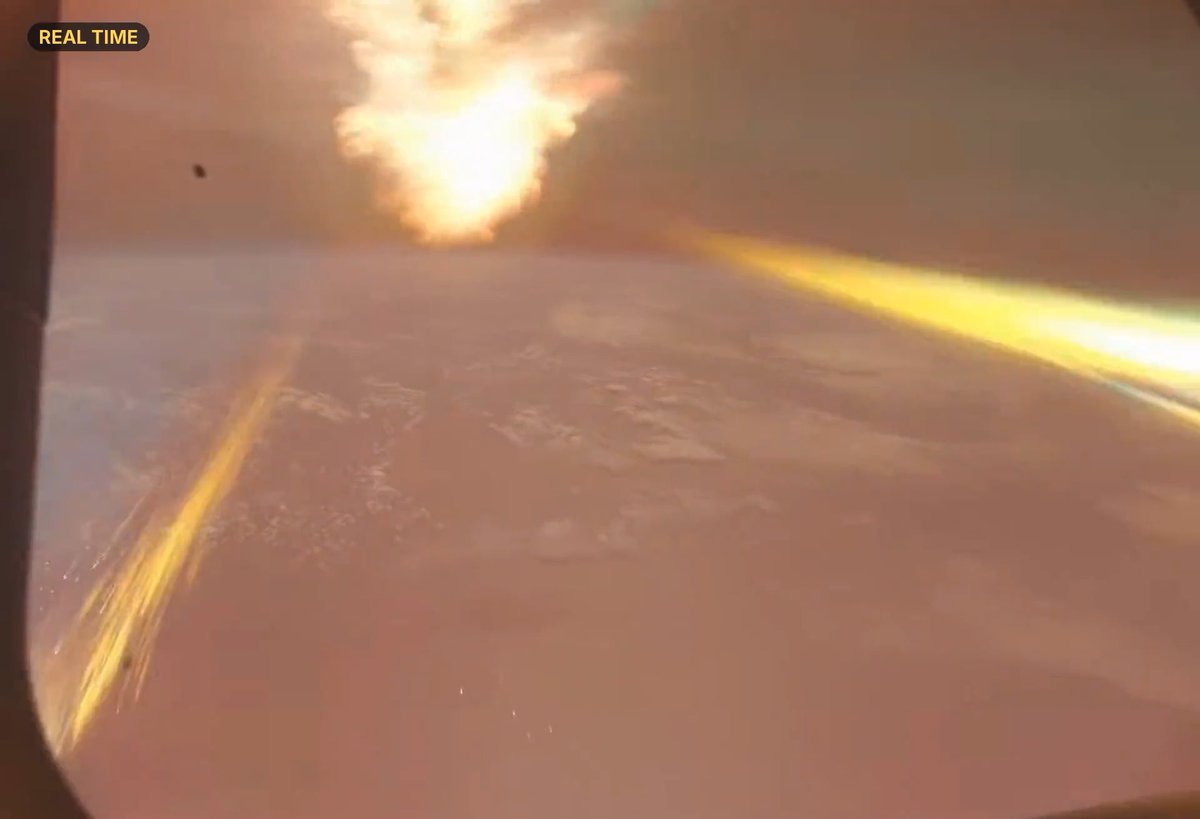 A view from space showing what appears to be a missile or rocket launch with bright light and smoke visible against the curvature of Earth, labeled 'REAL TIME' in the corner.