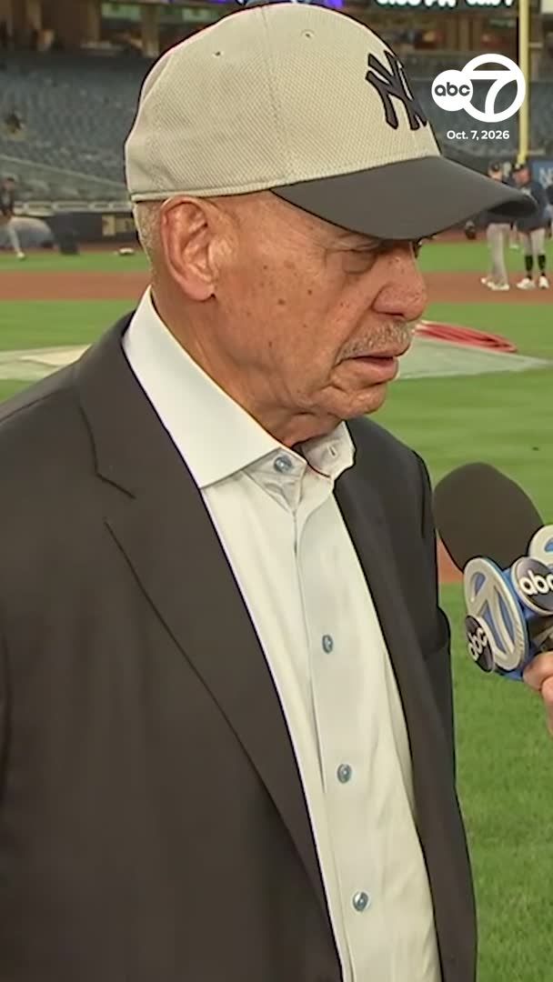 An older man wearing a New York Yankees cap and a brown suit jacket over a white button-down shirt is being interviewed on a baseball field. An ABC 7 microphone is visible, along with an on-screen graphic dated 'Oct. 7, 2026.'