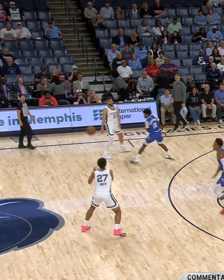 Memphis Grizzlies player #27 and teammates in white uniforms play against defenders in blue on the court at FedExForum, with a referee and spectators visible in the stands behind an advertisement reading "International Paper" and "Memphis." The image captures the moment setting up the play mentioned in the post, likely showing Franz Wagner (#27) about to pass or position himself for a play to Goga Bitadze for a slam dunk.