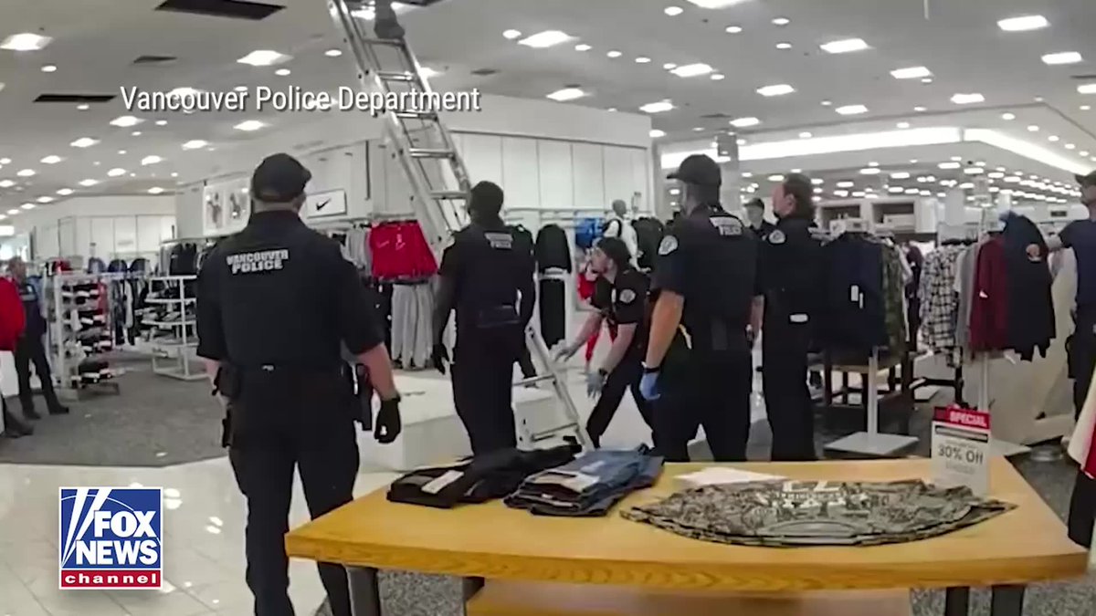 Vancouver Police Department officers respond inside a department store, likely Vancouver Mall, with a ladder extended to the ceiling where a burglary suspect allegedly hid for over an hour, as indicated by the "Vancouver Police Department" and "FOX NEWS channel" text overlays on the scene.