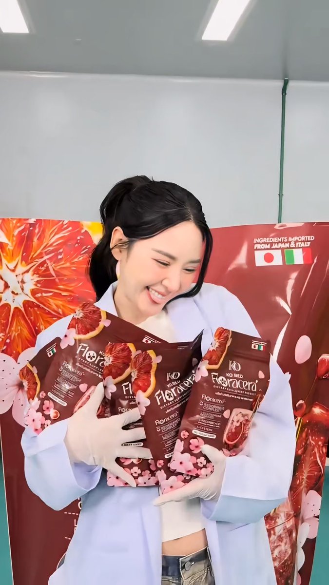A smiling woman wearing white gloves and a light blue shirt holds multiple packets of "Floracera" beverages, with a backdrop reading "INGREDIENTS IMPORTED FROM JAPAN & ITALY."
