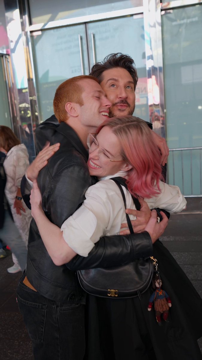 Director Terry Matalas shares a warm group hug with Ruaridh Mollica and Emily Hampshire from "VisionQuest," the series premiering October 14th, celebrating a joyful moment ahead of the show's debut.