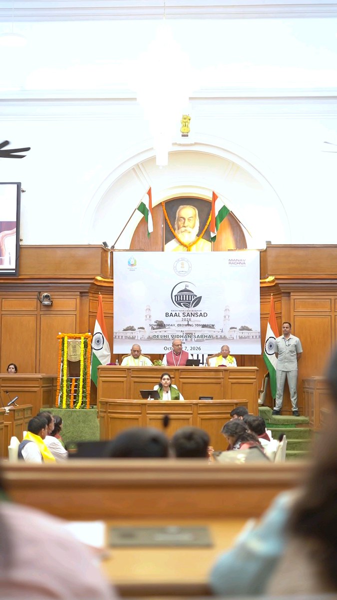 Interior of a legislative assembly hall with Indian flags, a portrait on the wall, and a banner reading 'BAAL SANSAD 1926', 'DELHI VIDHAN SABHA 1952', and dated 'Oct 7, 2026'.