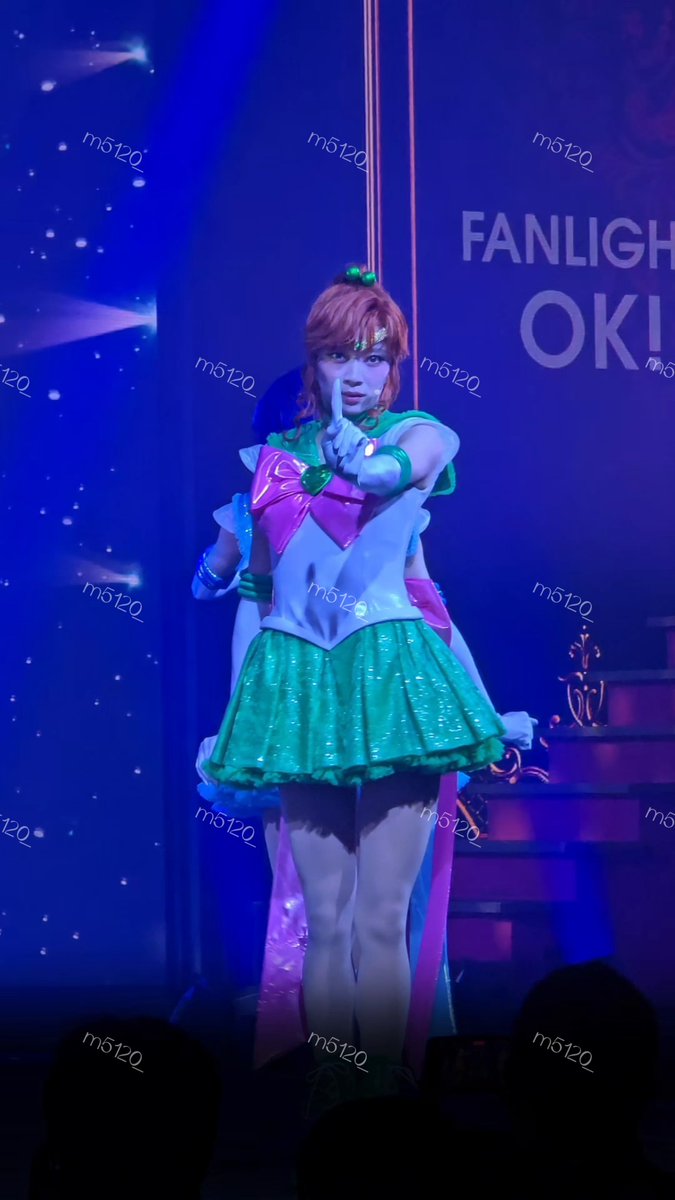 A cosplayer in a Sailor Jupiter costume poses with a peace sign on stage, with a 'FANLIGHT' sign visible behind them and an 'm5120_' watermark across the image.