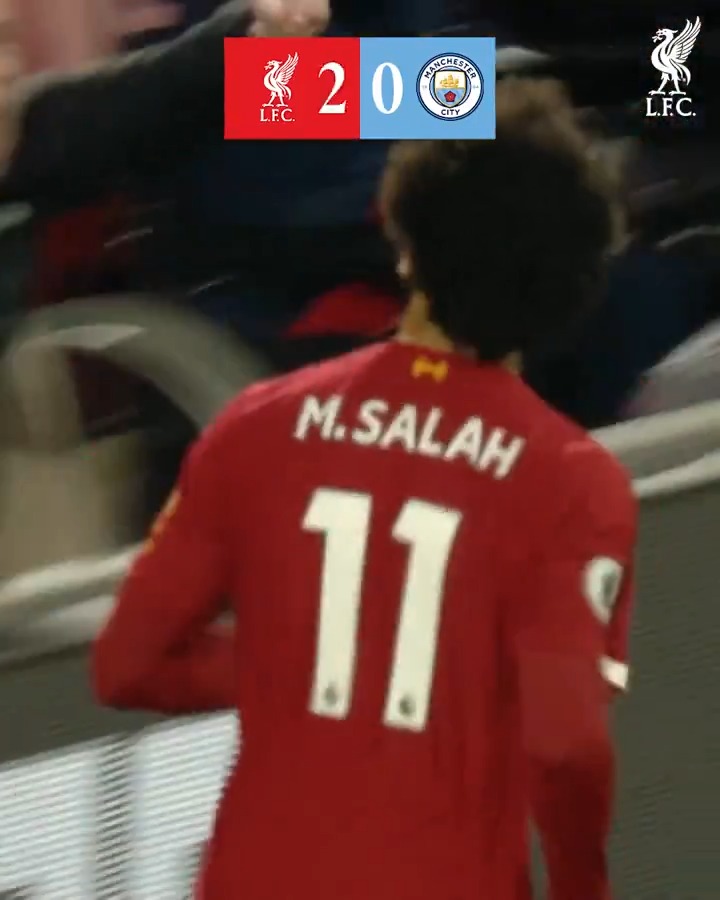 Liverpool's M. Salah (jersey #11) celebrates on the pitch with the scoreboard showing a 2-0 lead over Manchester City, complementing the post about the Reds' trio's dominant performance against City.
