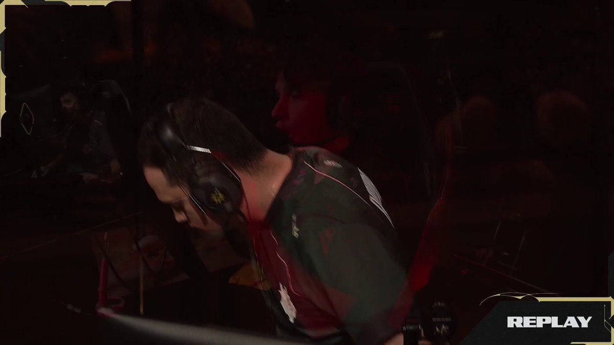 A gamer wearing a headset and team jersey is shown hunched over during a competitive esports match, with a 'REPLAY' graphic visible in the corner.