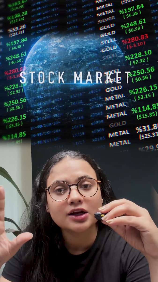 A young woman wearing glasses holds a small microphone while speaking, with a vibrant stock market backdrop behind her displaying the words "STOCK MARKET" alongside a globe graphic and scrolling green and red ticker data showing commodities like METAL, SILVER, GOLD, and STEEL with prices such as %197.84, %248.61, and %280.83. The financial imagery directly relates to the post's warning about a $75 trillion AI bubble in the US stock market, providing a fitting visual for discussing market volatility and investor concerns.