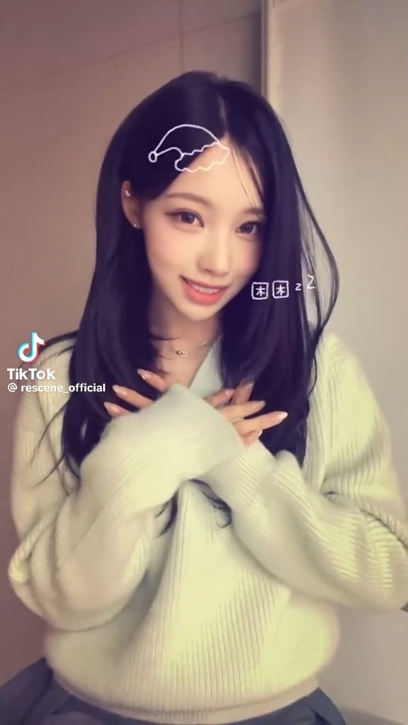 A young woman with long dark hair wearing a light green sweater smiles at the camera, with TikTok branding visible and a watermark for '@rescene_official'.