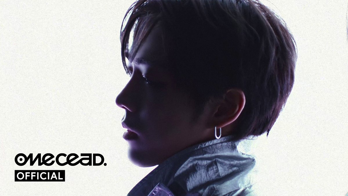 A side-profile portrait of a person with short dark hair wearing a small hoop earring, with "OMOCEAD. OFFICIAL" text in the bottom left.