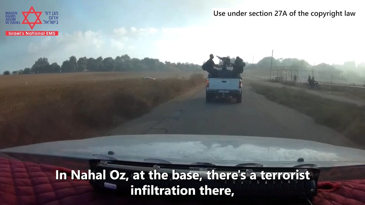 A dashcam view shows a pickup truck carrying people in the back driving down a dusty rural road; text reads 'In Nahal Oz, at the base, there's a terrorist infiltration there,' with 'Magen David Adom in Israel' logo and 'Use under section 27A of the copyright law' notice.