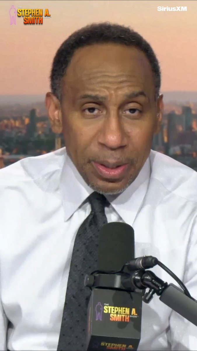 The image shows a man in a white dress shirt and black tie speaking into a microphone branded with "The Stephen A. Smith Show" logo on SiriusXM, set against a city skyline backdrop at sunset. The post's text about catching a ball at Yankee Stadium appears unrelated to the image, which simply captures a moment from the sports talk show broadcast.