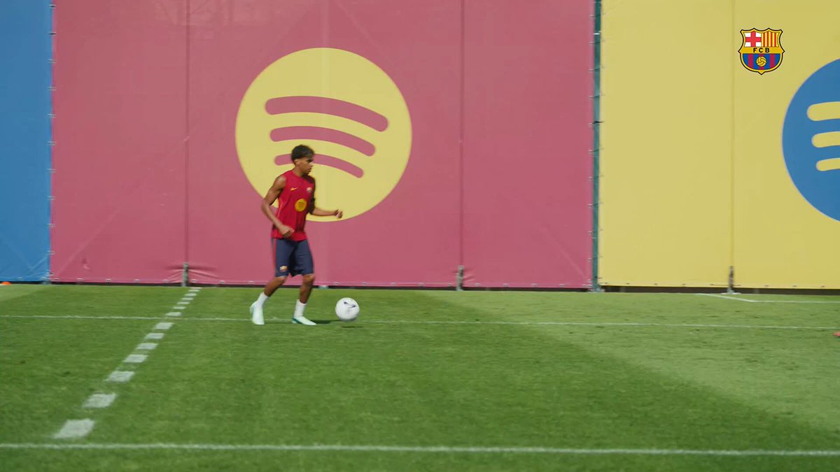 A young FC Barcelona player, likely Lamine Yamal, dribbles a soccer ball during a training session on the pitch, with the team's crest visible in the upper right corner. The image captures a moment of skillful play, reflecting the post's caption "O show do Lamine. Rabiscou geral!" which translates to "Lamine's show. Dazzled everyone!"