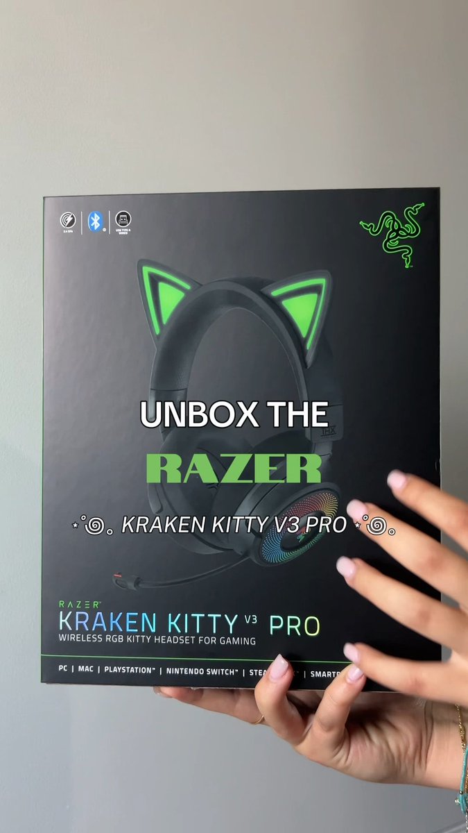 A person holding a Razer Kraken Kitty V3 Pro headset box with text overlay reading 'UNBOX THE RAZER KRAKEN KITTY V3 PRO'.