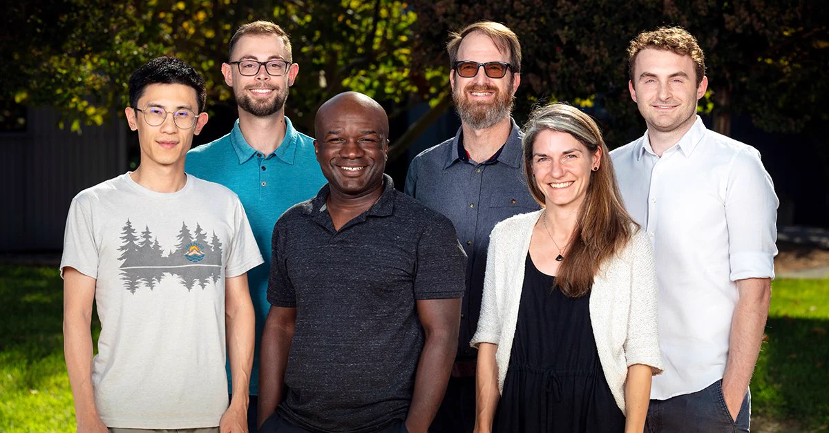 six people stand in a group outside