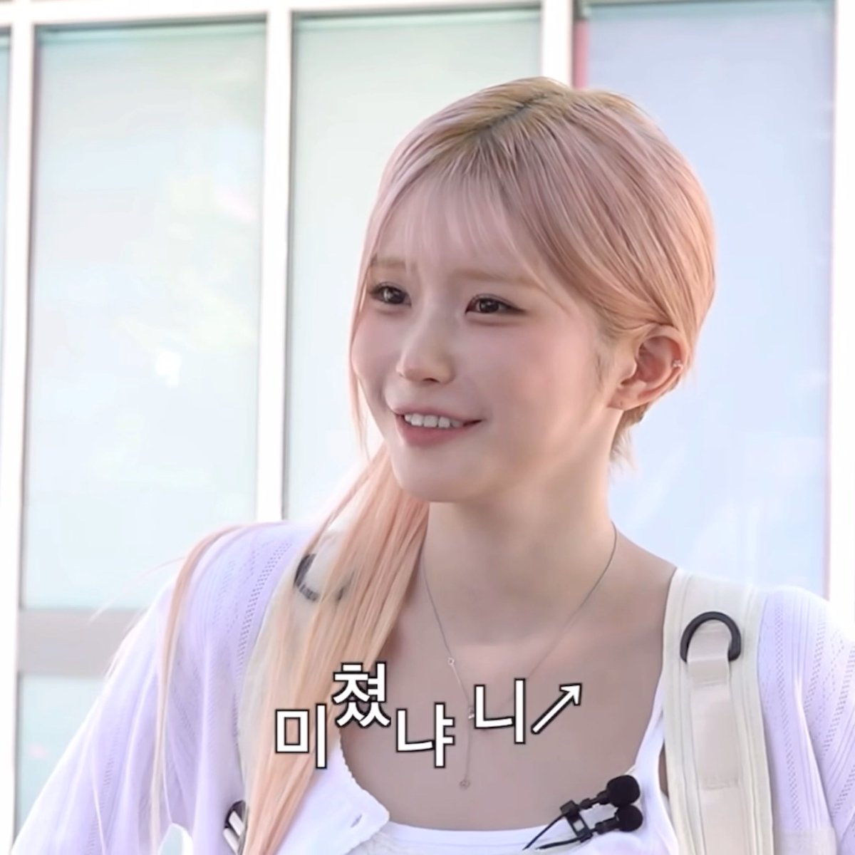 A smiling young woman with long blonde hair in a white top, with Korean text reading '미쳤냐↗' overlaid on the image.