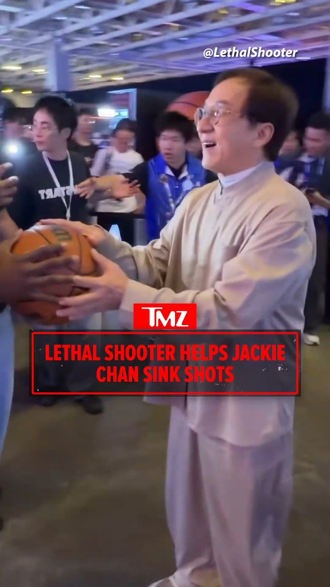 A vertical TMZ-style clip shows Jackie Chan in a light beige outfit and glasses holding a basketball while surrounded by several people in a crowded indoor venue, including a man in a black shirt at left and others filming with phones. A basketball is also visible near the upper center behind him. The frame includes the on-screen text “@LethalShooter” at the top right and a red lower-third reading “TMZ” and “LETHAL SHOOTER HELPS JACKIE CHAN SINK SHOTS,” matching the post’s description of Lethal Shooter assisting Jackie Chan with a jump shot.