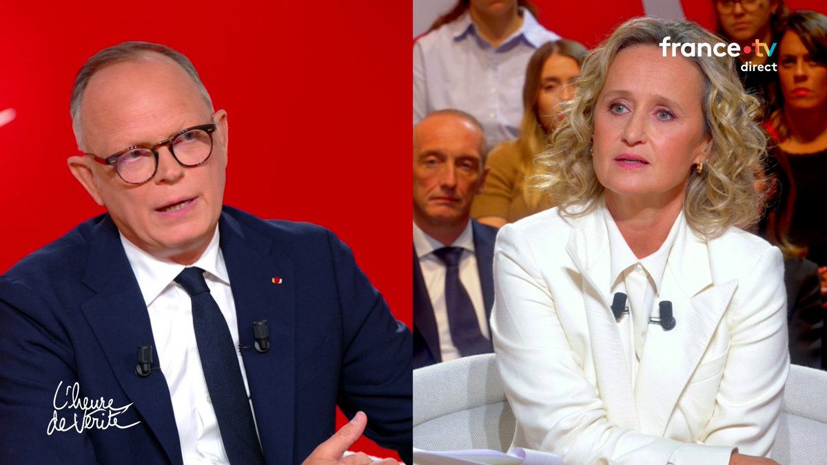 A split-screen from a French TV debate ('L'heure des vérité' on France.tv), showing an older man in glasses on the left and a blonde woman in a white blazer on the right.