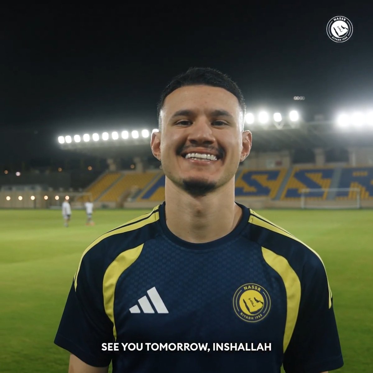 The post features a smiling Abdullah Al-Humidan in his Al-Nassr training kit (with the club's "NASSR RIYADH 1955" crest and Adidas logo visible), filmed at night in a stadium under bright floodlights. The on-screen caption reads "SEE YOU TOMORROW, INSHALLAH," matching his message to fans about an upcoming match with tickets linked via victoryarena.com.