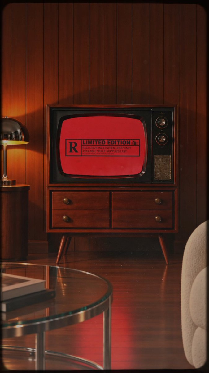 A vintage wood-paneled television set displays a red screen with a stamp reading 'R LIMITED EDITION EXCLUSIVE HALLOWEEN DROP ONLY AVAILABLE WHILE SUPPLIES LAST' in a dimly lit retro living room.