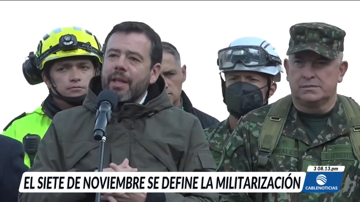 A news broadcast screenshot from CableNoticias showing a man in a green jacket speaking into a microphone, flanked by a firefighter and military personnel; the on-screen graphic reads 'EL SIETE DE NOVIEMBRE SE DEFINE LA MILITARIZACIÓN' with a timestamp of 3 08.13.pm.