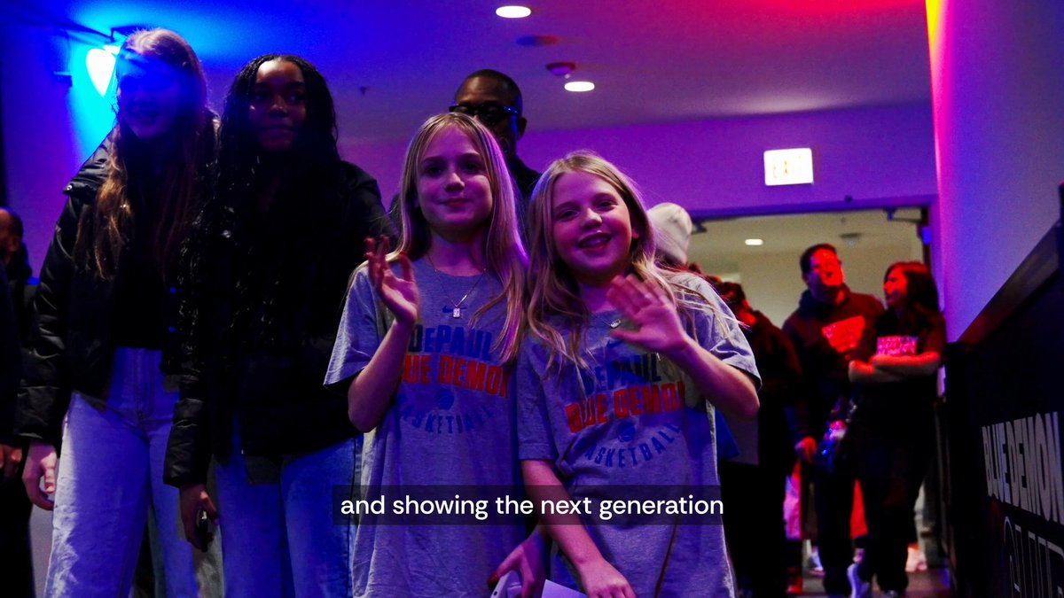 Two young girls wear DePaul Blue Demons Basketball t-shirts, smiling and waving at the camera as they attend the launch of DePaul NOW (Network of Women), an initiative that brings together the DePaul community to inspire and open doors for the next generation of Blue Demons.