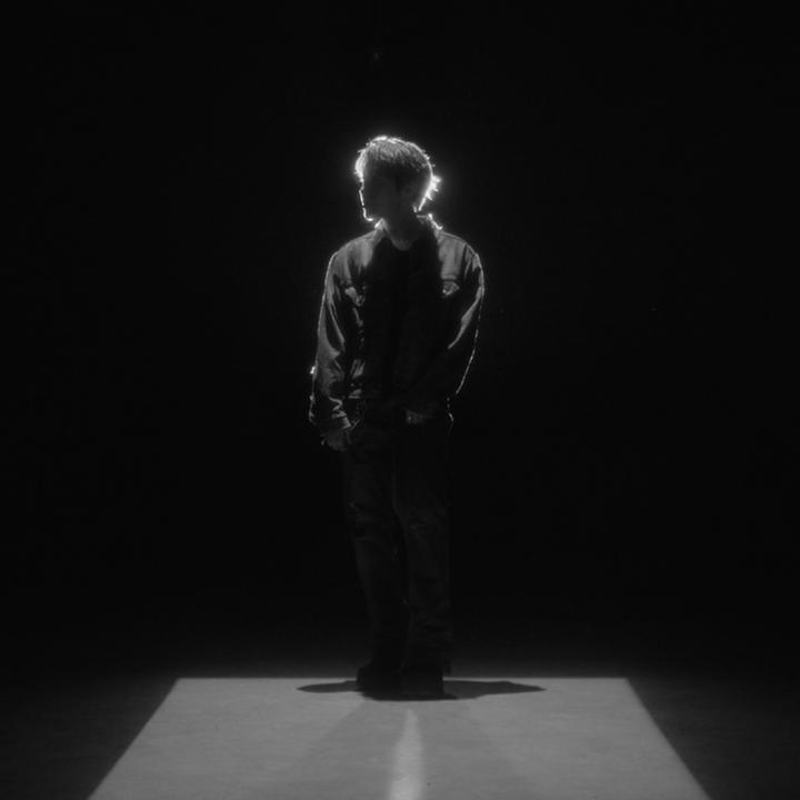 A solitary figure stands in a dramatic black-and-white spotlight, embodying the anticipation of "Someone's about to arrive soon"—mirroring the post's tease of the Galaxy Z Fold8 reveal. The staged silhouette suggests a grand unveiling, hinting that the new foldable experience is truly worth the wait.