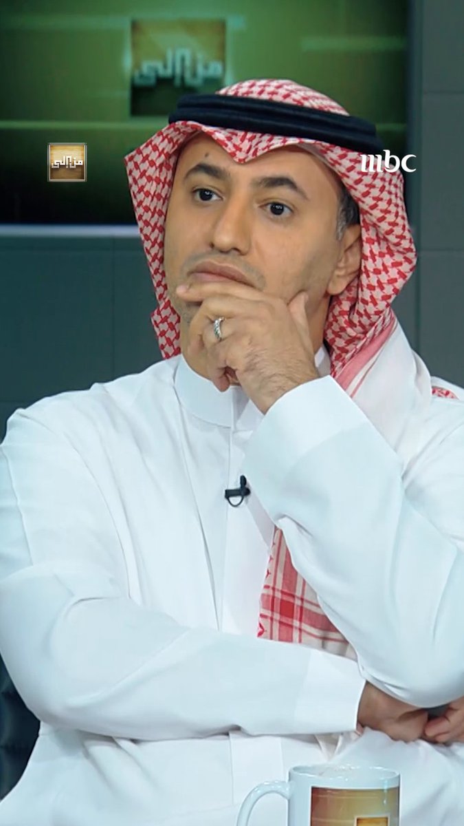 A man in traditional Saudi attire (white thobe and red-and-white shemagh) sits on an MBC TV panel, resting his hand thoughtfully on his chin.