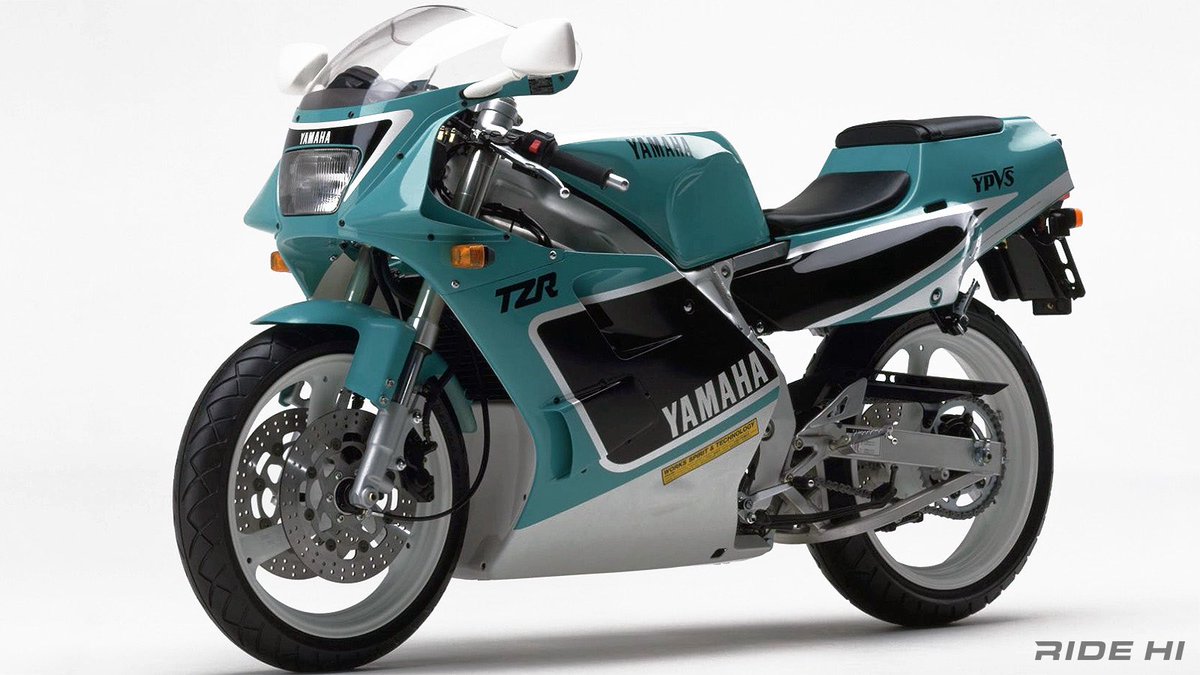 PutiMotor's tweet photo. '89 ヤマハ「TZR250」

市販レーサーTZ250と同時開発。

低重心化と深いバンク角で、運動性を一気に高める狙いの後方排気を採用。

規制値上限の45PS/9,500rpmに3.8kgm/8,000rpmのパワースペックで、中速域からまっしぐらにピーク回転域へ吹き上がる力強さをアピール。

ハンドリングは2スト250では経験したことのない低重心な安定性で、前輪の素早い回頭性と少し頑固に感じるほど安定感を崩さないヤマハらしさ。

しかしレースの世界で更なるエンジンパフォーマンスを求め、一軸Vツインが優位なことから、後方排気TZRは僅か2シーズンで終焉を迎えた。

https://t.co/z8RSrJKBec