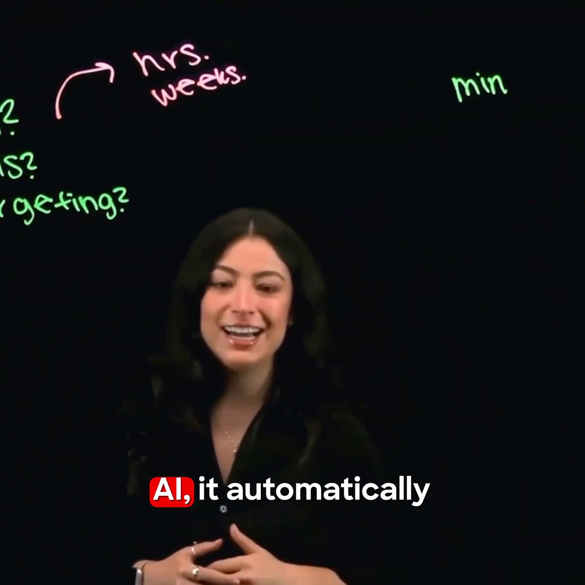 A woman with dark hair smiling and speaking in front of a black background with handwritten text about hours, weeks, and minutes, with a caption reading 'AI, it automatically.'