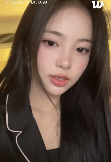 A selfie of a young woman with long dark hair wearing a black top, showing the numbers '185,242' and '1,431,098' along with a 'W' logo.