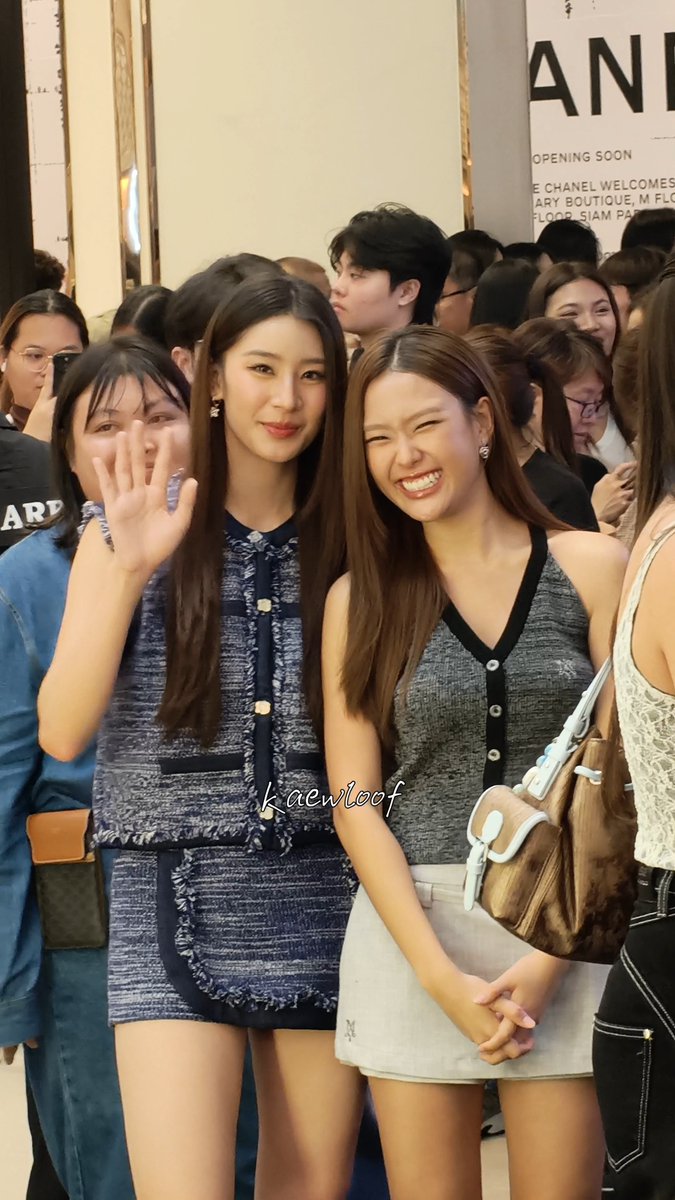 Two young women pose together at a Chanel boutique event, with a banner behind them reading "OPENING SOON" and "CHANEL WELCOMES YOU," while one waves and the other flashes a playful smile holding a Louis Vuitton bag. The watermark "kaewloof" appears across the image, and the scene captures a fan-meeting moment related to Mingming Nepjune at the Siam Paragon/Center BIFW 2026 event.