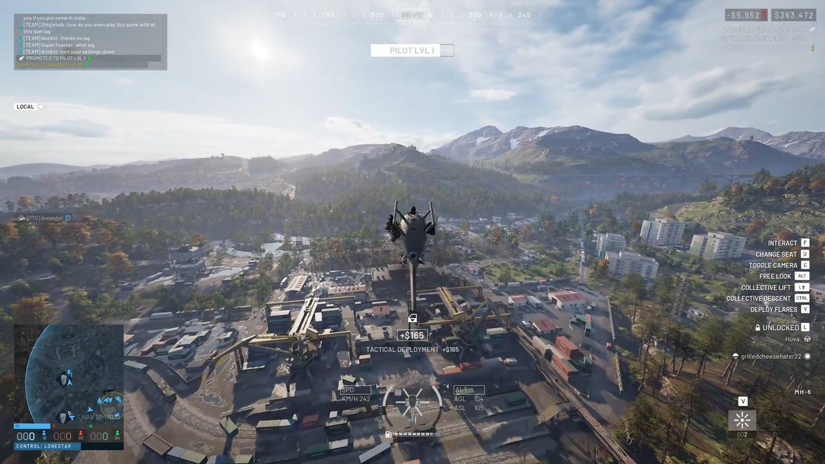 A video game screenshot showing a helicopter flying over a mountainous terrain with buildings below, featuring HUD elements like a minimap, chat window, and control options.