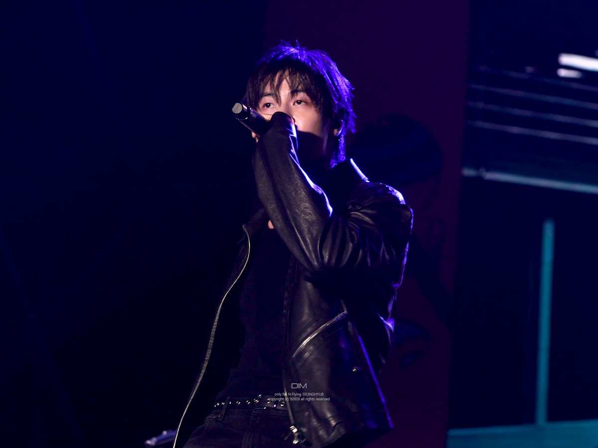 Concert photo of a performer singing into a microphone while wearing a black leather jacket, with a watermark crediting "only ☆ Fly!ing SEUNGHYUN © 2026 all rights reserved".