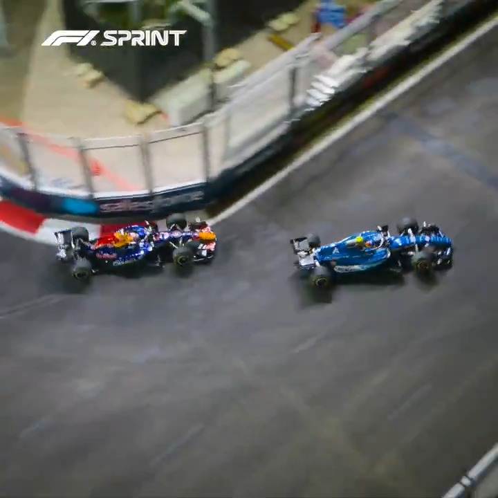 Three Formula 1 cars race along a street circuit under bright lights, with the "F1 SPRINT" logo visible in the top left corner, capturing the nighttime action of the Singapore Grand Prix sprint race.