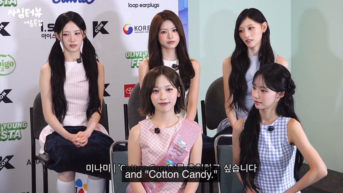 Five members of the K-pop group ILLIT (including Minami) are interviewed at the KCON event, discussing their song "Cotton Candy" as shown in the subtitles.