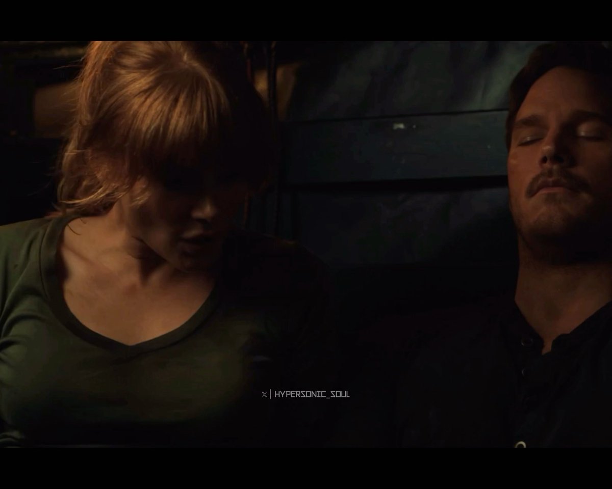 A woman with blonde hair in an olive green top sits in dim lighting beside a sleeping man with a beard, with "X | HYPERSONIC_SOUL" watermark visible at the bottom. The image aligns with the post's claim about Bryce Dallas Howard in olive green attire, though the lighting here is too dark to fully appreciate the outfit.